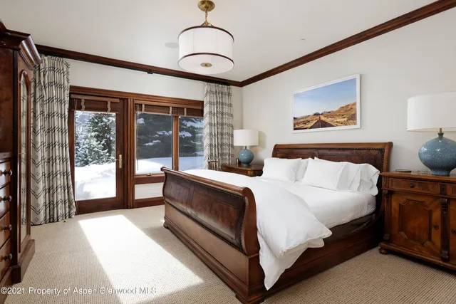 a bedroom with a large bed and a chandelier next to a window