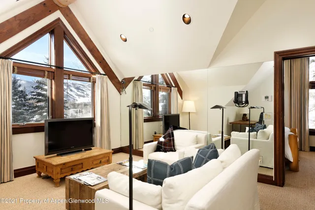 a living room with furniture a flat screen tv and a floor to ceiling window