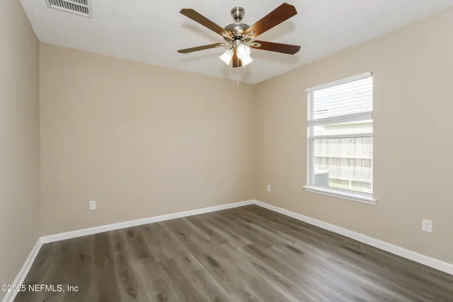 an empty room with a window and a fan