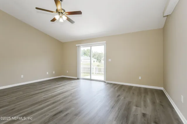 an empty room with wooden floor fan and windows