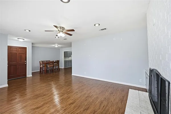 an empty room with wooden floor and a ceiling fan