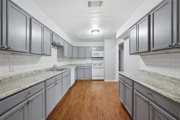 a kitchen with granite countertop stainless steel appliances a sink stove refrigerator and cabinets