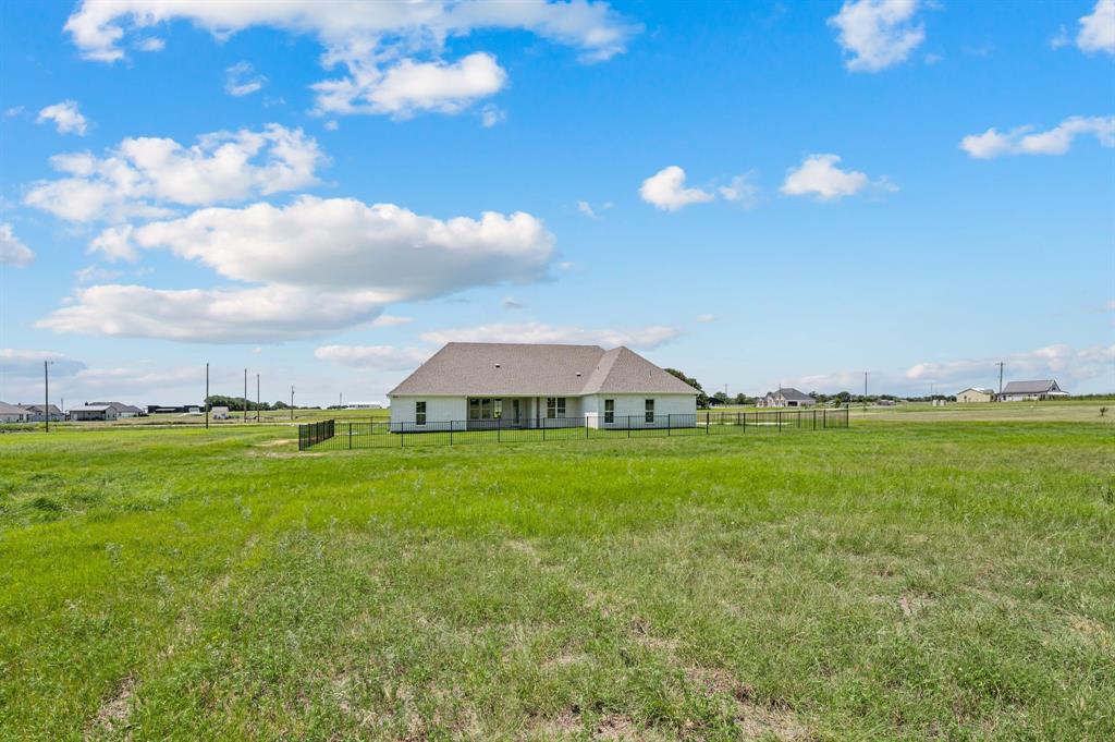 2705 Gospel Road Tolar, TX 76476 - Photo 33 of 36 Expansive green lawn surrounds the property, featuring a single-story residence with a light-colored exterior and a grey shingle roof