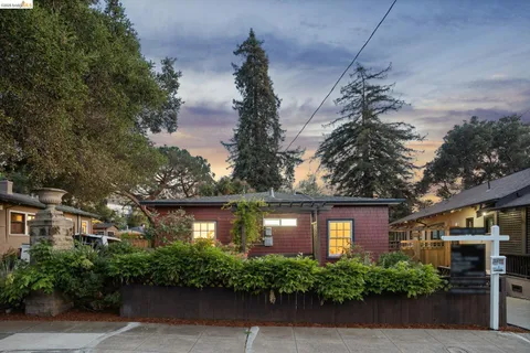 a view of a brick house with a small yard and large trees