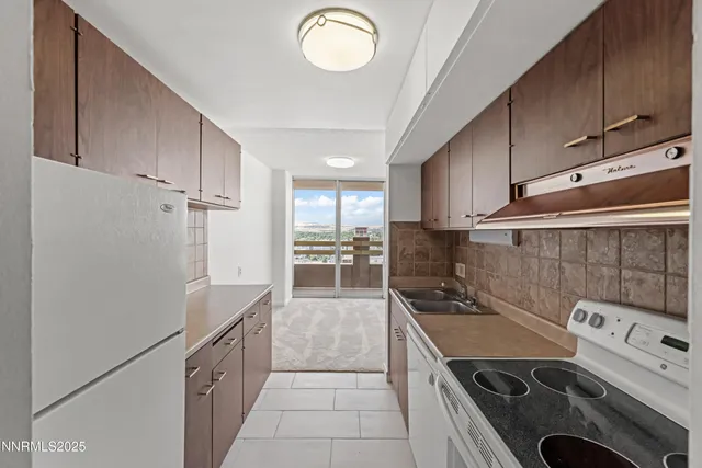 a kitchen with granite countertop a stove a sink and a refrigerator