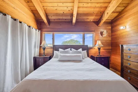 a bedroom with a bed and large windows