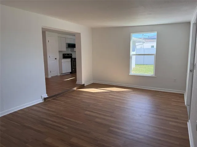 an empty room with wooden floor closet and windows