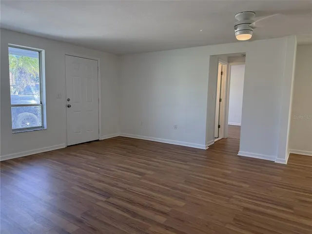 an empty room with wooden floor and windows