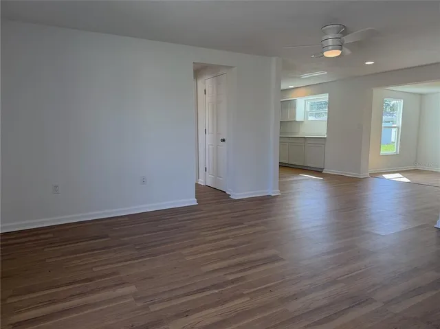 an empty room with wooden floor cabinet and windows