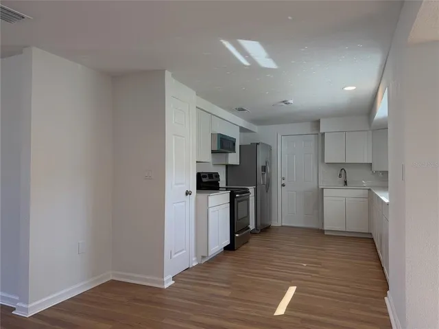 a kitchen with a refrigerator stove and wooden floor
