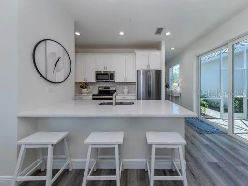 a kitchen with stainless steel appliances a table chairs refrigerator and microwave