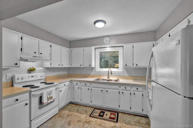a kitchen with granite countertop a white refrigerator oven a sink dishwasher and white cabinets with wooden floor