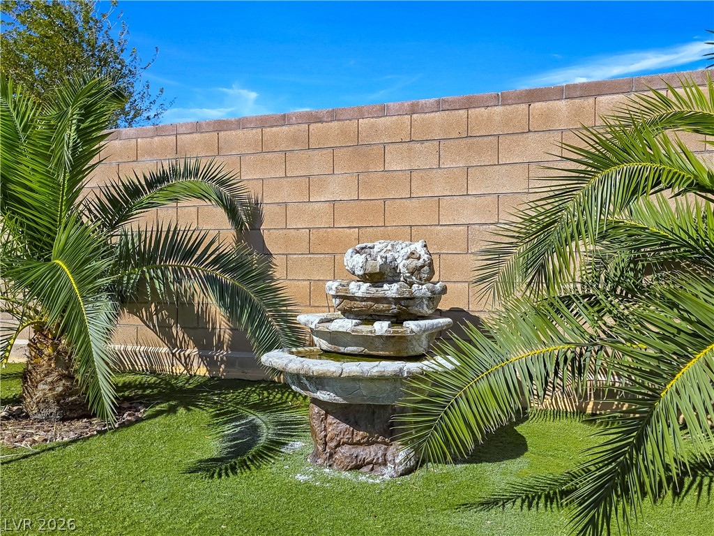 2485 Morrow Ridge Place Laughlin, NV 89029 - Photo 36 of 40 A tranquil outdoor space features lush artificial turf and a decorative stone fountain against a privacy wall.
