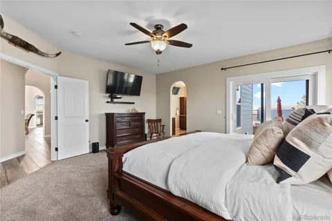 a bedroom with a bed a flat screen tv and a ceiling fan