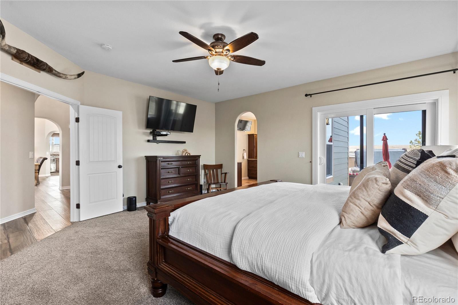 41900 East Muirfield Loop Elizabeth, CO 80107 - Photo 14 of 26 a bedroom with a bed a flat screen tv and a ceiling fan