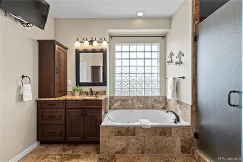 a bathroom with a granite countertop tub sink and mirror