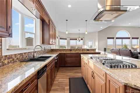 a kitchen with kitchen island granite countertop a sink stove and cabinets