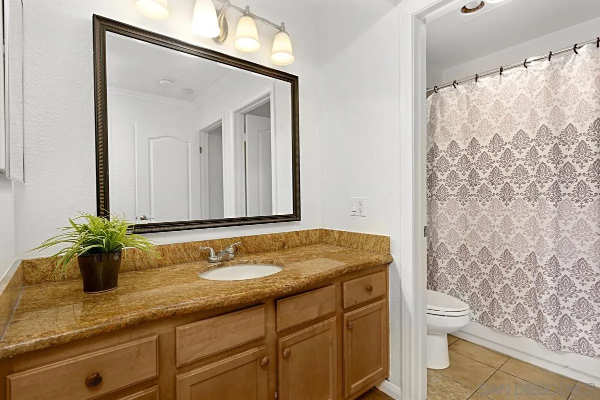 615 Fredricks Avenue, Unit 159 Oceanside, CA 92058 - Photo 19 of 26 a bathroom with a granite countertop sink a toilet and a mirror