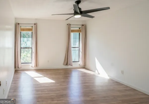 a view of an empty room with wooden floor and a window