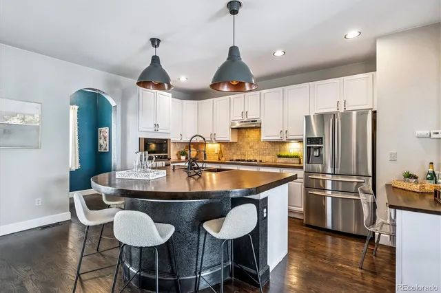 a kitchen with stainless steel appliances a dining table chairs sink and cabinets