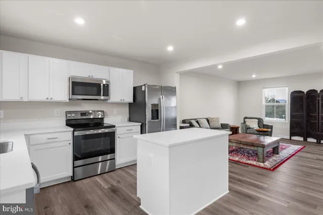 a living room with stainless steel appliances furniture and a wooden floor