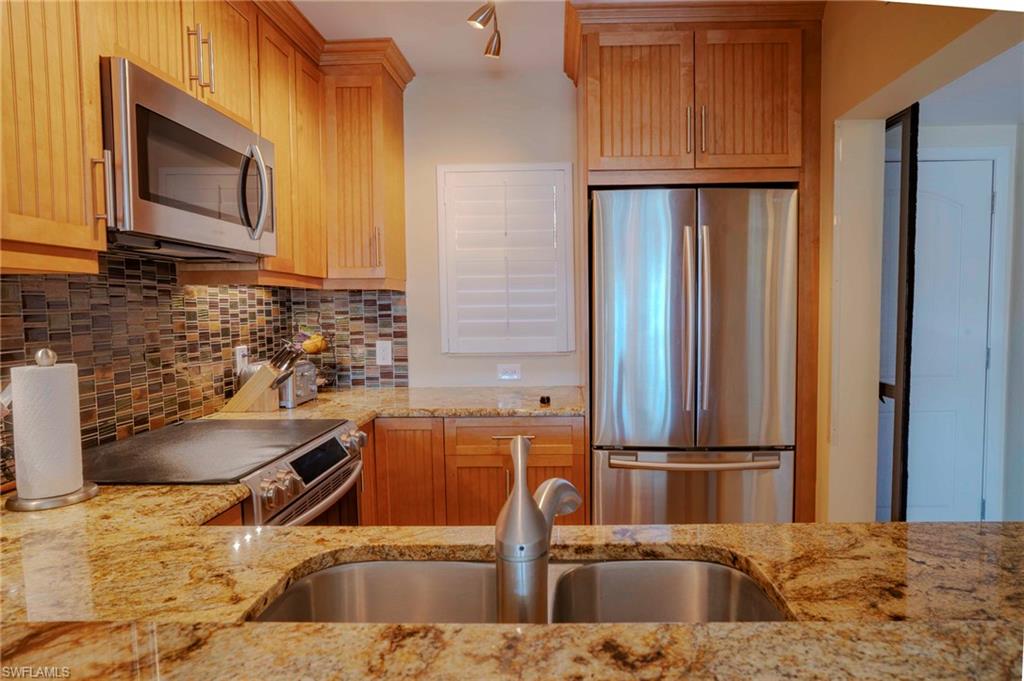 805 River Point Drive, Unit 103C Naples, FL 34102 - Photo 15 of 27 a kitchen with stainless steel appliances granite countertop a sink and a refrigerator
