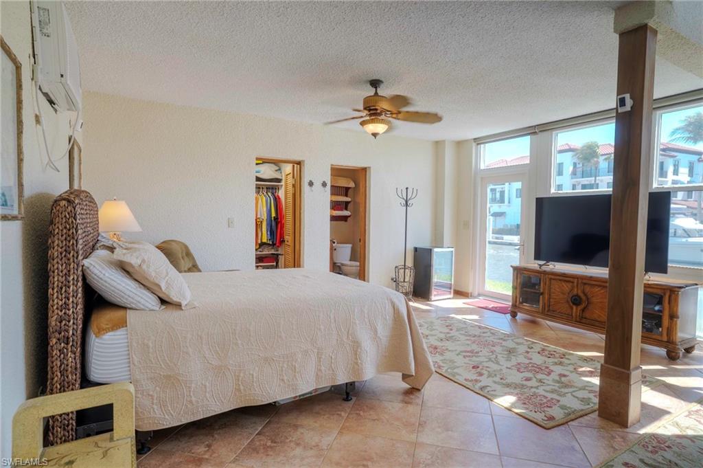 805 River Point Drive, Unit 103C Naples, FL 34102 - Photo 17 of 27 a bedroom with a bed and a flat tv screen on dresser