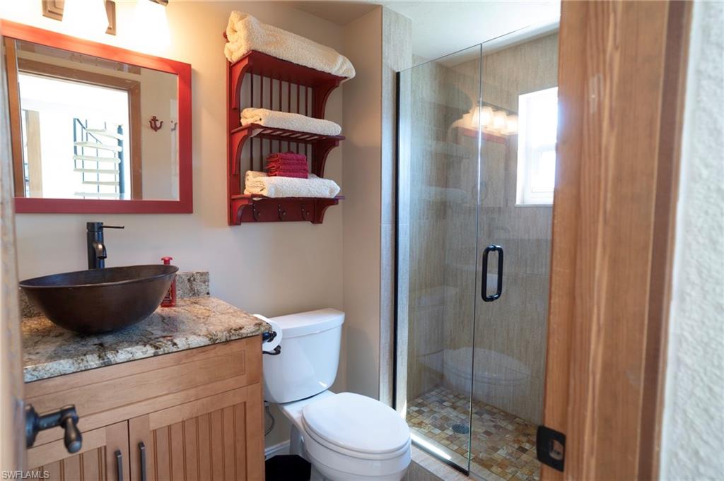 805 River Point Drive, Unit 103C Naples, FL 34102 - Photo 19 of 27 a bathroom with a granite countertop toilet sink and shower