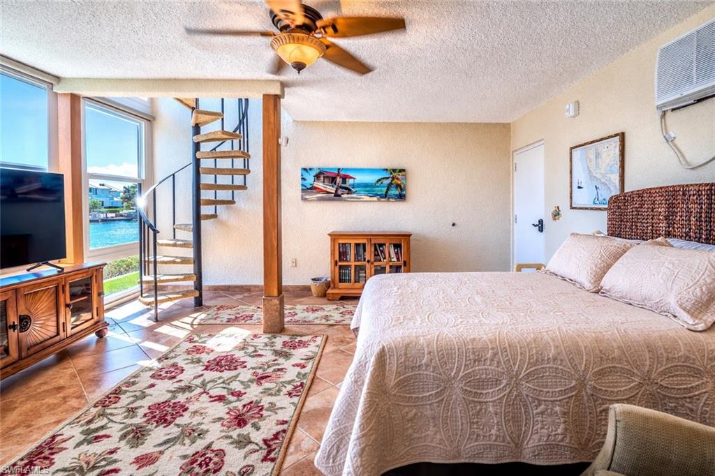 805 River Point Drive, Unit 103C Naples, FL 34102 - Photo 20 of 27 a bedroom with a bed a dresser and flat screen tv
