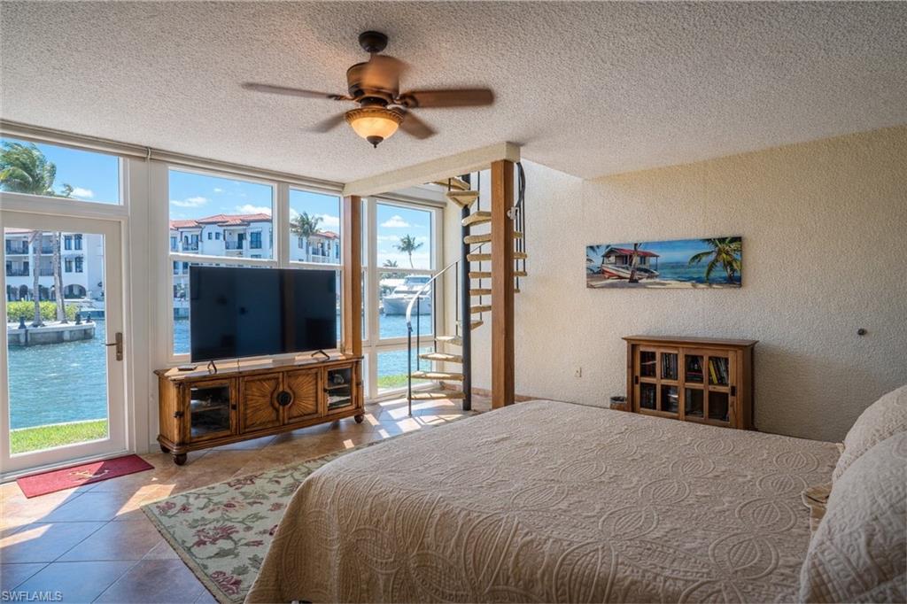 805 River Point Drive, Unit 103C Naples, FL 34102 - Photo 21 of 27 a bedroom with a bed and a flat tv screen on dresser