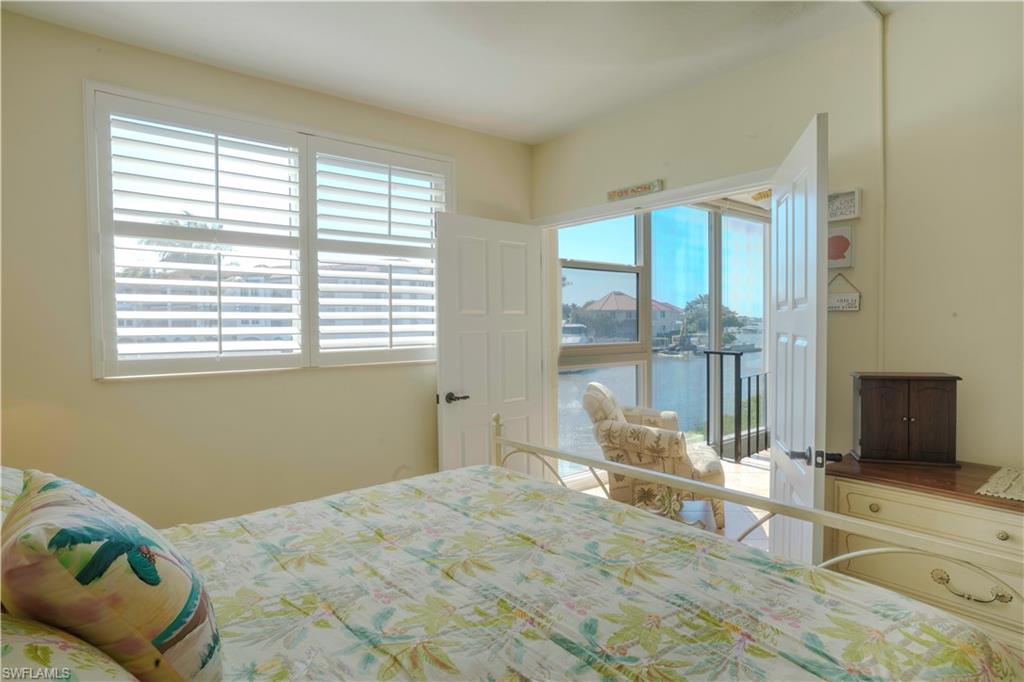 805 River Point Drive, Unit 103C Naples, FL 34102 - Photo 23 of 27 a bedroom with a bed and large windows