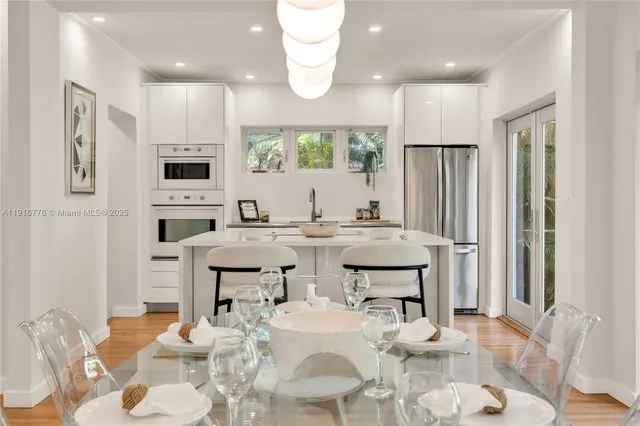 a dining room with wooden floor a chandelier a glass table and chairs