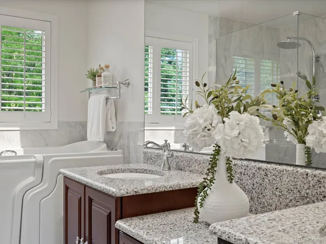 a en suite bathroom with a granite countertop sink a mirror and a bathtub