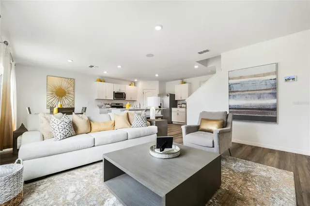 a living room with furniture kitchen view and a large window
