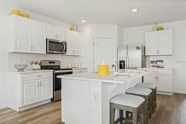 a kitchen with stainless steel appliances granite countertop a sink a stove a refrigerator cabinets and chairs