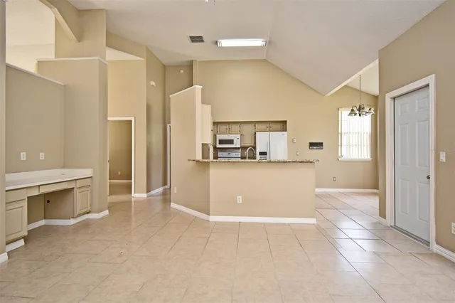 a view of an empty room with window and chandelier fan