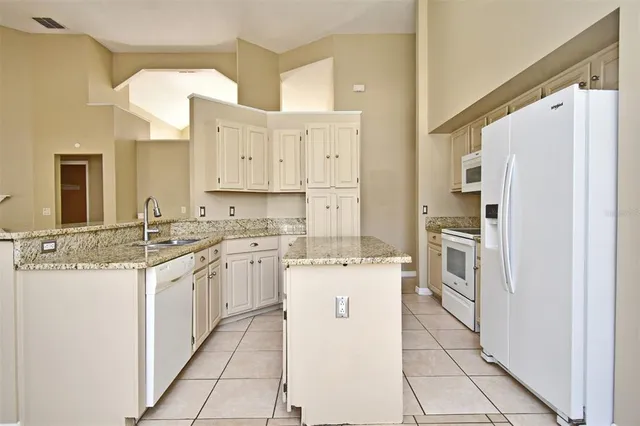 a kitchen with granite countertop a sink and dishwasher with white cabinets