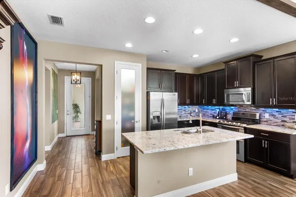 a kitchen with stainless steel appliances kitchen island granite countertop a sink stove and refrigerator