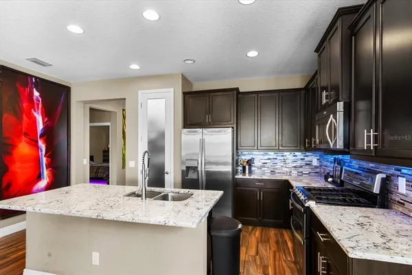 a kitchen with stainless steel appliances wooden floor and a refrigerator