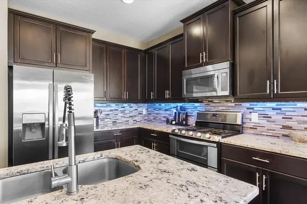 a kitchen with stainless steel appliances granite countertop a refrigerator stove and sink