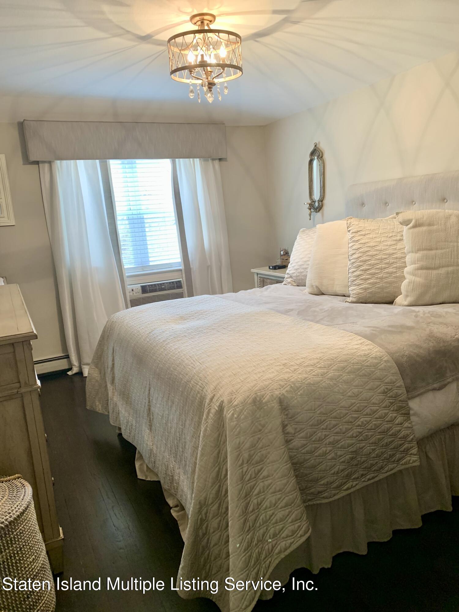 3482 Amboy Road, Unit 2A Staten Island, NY 10306 - Photo 9 of 15 a bedroom with a bed and a chandelier