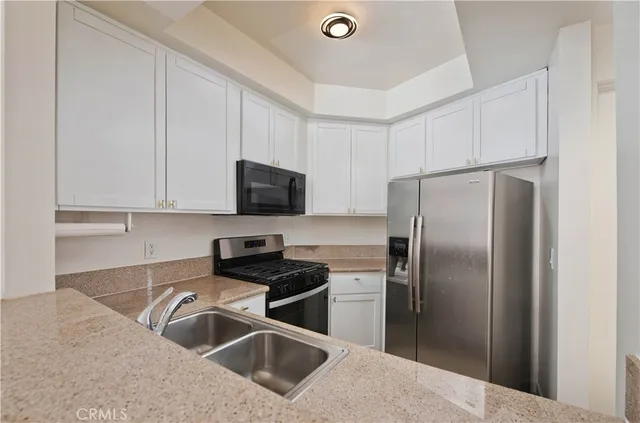a kitchen with stainless steel appliances granite countertop a refrigerator a sink a stove with white cabinets