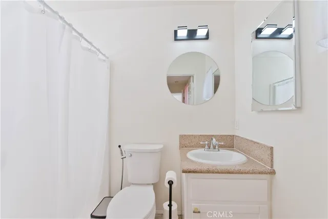 a bathroom with a granite countertop toilet sink and mirror