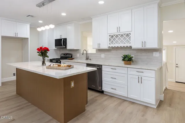 a kitchen with white cabinets appliances and a sink