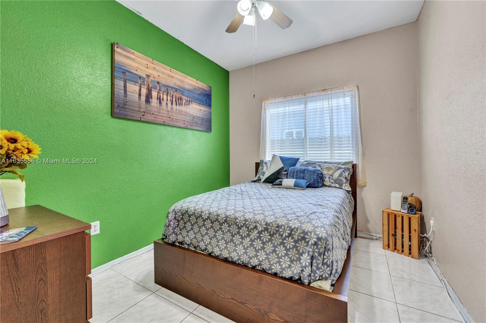 426 West 70th Street Hialeah, FL 33014 - Photo 9 of 26 a bed sitting in a bedroom next to a window with a chandelier
