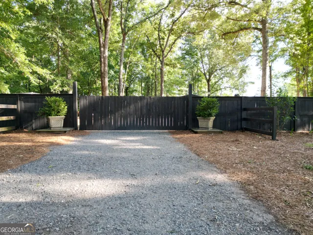 a backyard of a house with plants and tree with wooden fence