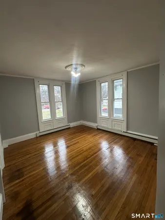 a view of an empty room with wooden floor and a window