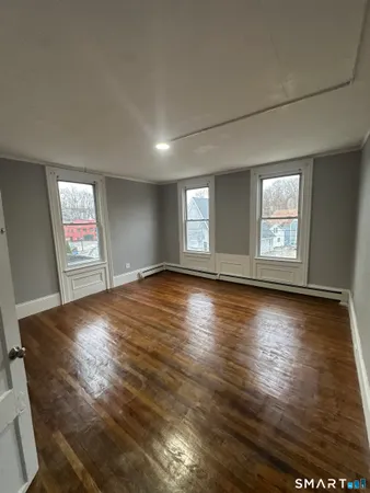 a view of empty room with window and wooden floor