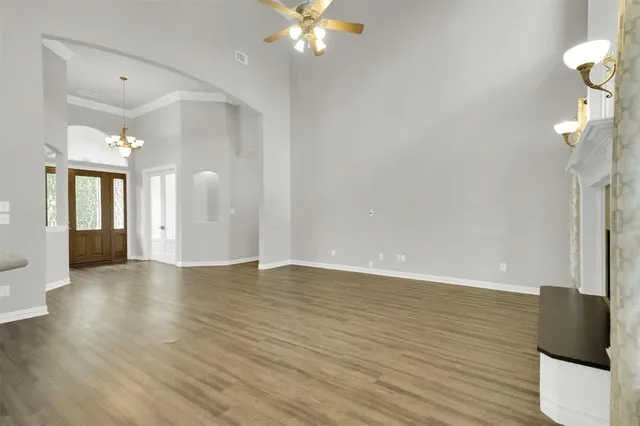 a view of an empty room with wooden floor and a chandelier