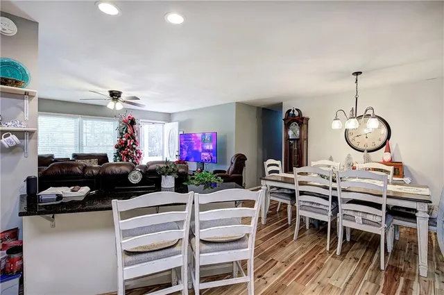a view of a dining room and livingroom with furniture wooden floor a rug a painting and a chandelier